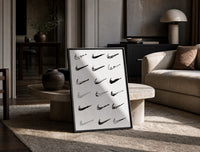 Various hand-drawn Nike swoosh logos print in a black frame leaning on a travertine table in a sunlit lounge