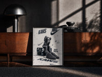 Black-framed KAWS Companion figure and sneaker print on a moody console with designer coffee-table books