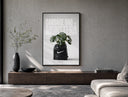 Monstera plant in Nike garbage bag poster framed above a wood console in a concrete-wall living room