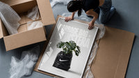 Monstera plant in Nike garbage bag framed print being unpacked from protective bubble wrap and a box