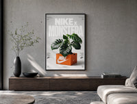 Monstera plant in Nike shoe box poster framed above a wood console in a concrete-wall living room