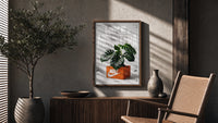Monstera plant in Nike shoe box poster framed above a fluted sideboard beside an olive tree