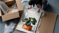 Monstera plant in Nike shoe box framed print being unpacked from protective bubble wrap and a box