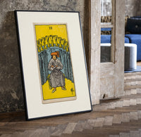 Seated man before nine golden cups print in a black frame leaning beside a vintage door on parquet