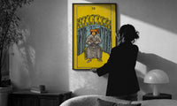 Nine of Cups print in a slim black frame being hung on a sunlit wall in a monochrome room