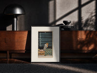 Black-framed Person seated with nine swords print on a moody console with designer coffee-table books