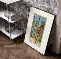 Man holding wooden staff among wands poster in a black frame leaning beside a shelf in a raw-plaster loft