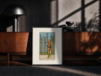 Black-framed Man holding wooden staff among wands print on a moody console with designer coffee-table books