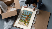 Man holding wooden staff among wands framed print being unpacked from protective bubble wrap and a box