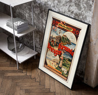 French coastal travel scenes poster in a black frame leaning beside a shelf in a raw-plaster loft