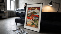 French coastal travel scenes print in a slim black frame leaning on a dark sofa in a concrete print studio
