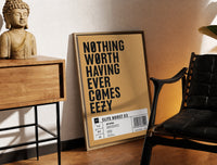 Brass-framed Motivational typography shoe box label print leaning in a warm styled corner by a sculpture