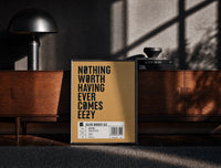 Black-framed Motivational typography shoe box label print on a moody console with designer coffee-table books