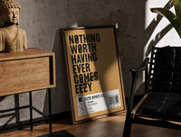 Motivational typography shoe box label print in a walnut frame between a wood side table and black leather chair