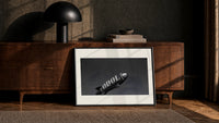 advertising blimp airship print in a black frame leaning against a walnut console in lamplight