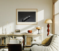 advertising blimp airship print in an oak frame above a mid-century book console with a vintage radio