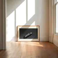 advertising blimp airship print in an oak frame on a sunlit wood floor beneath tall window light