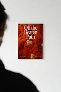 Person viewing the red plush Off the Beaten Path art print hung on a white gallery-style wall