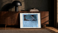 Elegant woman holding hand mirror print in a black frame leaning against a walnut console in lamplight