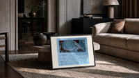 Elegant woman holding hand mirror print in a slim black frame leaning on a travertine coffee table