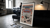 Orient Express railway travel poster print in a slim black frame leaning on a dark sofa in a concrete print studio