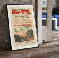 French Auvergne railway travel advertisement print in a black frame leaning beside a vintage door on parquet