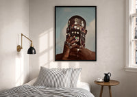 Ornate Headpiece with Fringe and Rings print in a black frame above a bed with striped linens