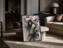 Long-haired man with giant white snake print in a black frame leaning on a travertine table in a sunlit lounge