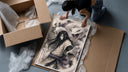 Long-haired man with giant white snake framed print being unpacked from protective bubble wrap and a box