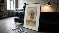 Page holding cup with fish print in a slim black frame leaning on a dark sofa in a concrete print studio