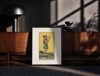 Black-framed Youth holding pentacle coin print on a moody console with designer coffee-table books
