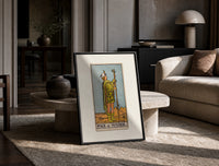 Page of Wands tarot figure print in a black frame leaning on a travertine table in a sunlit lounge