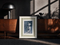 Black-framed Elegant woman with perfume bottle print on a moody console with designer coffee-table books