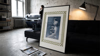 Elegant woman with perfume bottle print in a slim black frame leaning on a dark sofa in a concrete print studio