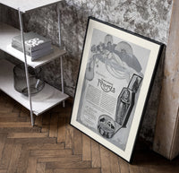 Reclining Egyptian woman perfume advertisement poster in a black frame leaning beside a shelf in a raw-plaster loft