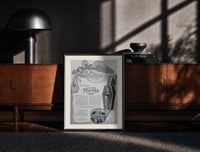 Black-framed Reclining Egyptian woman perfume advertisement print on a moody console with designer coffee-table books