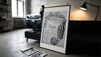 Reclining Egyptian woman perfume advertisement print in a slim black frame leaning on a dark sofa in a concrete print studio