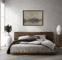 River bridge with city skyline print in a dark wood frame above a rattan bed on a plaster wall