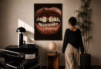 Parted Lips with Gold-Tone Grillz print in a black frame on a sunlit plaster wall, a woman looking on beside a mushroom lamp