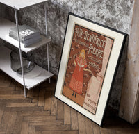 Young girl in red nightgown poster in a black frame leaning beside a shelf in a raw-plaster loft