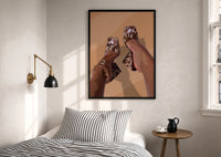 Cowhide Mules and Chain Anklet print in a black frame above a bed with striped linens