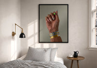 Patterned Nails with Stacked Watches print in a black frame above a bed with striped linens