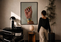 Patterned Nails with Stacked Watches print in a black frame on a sunlit wall with a viewer