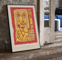 Abstract face with small figures print in a black frame leaning beside a vintage door on parquet