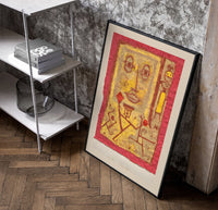 Abstract face with small figures poster in a black frame leaning beside a shelf in a raw-plaster loft
