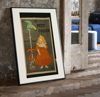 Girl in red dress eating biscuit print in a black frame leaning beside a vintage door on parquet