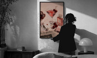 Pink Drink, Cherries and Perfume print in a slim black frame being hung on a sunlit wall in a monochrome room