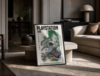 Overgrown PlayStation console with controller print in a black frame leaning on a travertine table in a sunlit lounge