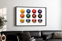 Twelve Pool Balls Solids and Stripes print in a black frame above a black leather sofa on a white wall