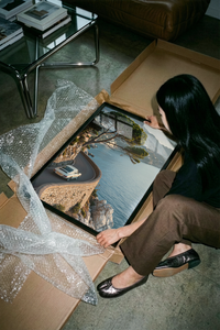 Porsche 911 coastal road print showing curving asphalt placed beside a protective shipping tube on a table